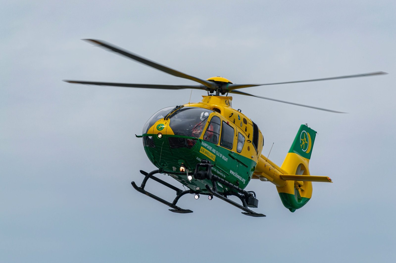 A green and yellow helicopter flying in the sky